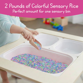 7 Days of Play scooping and pouring with pastel rice in a bin.