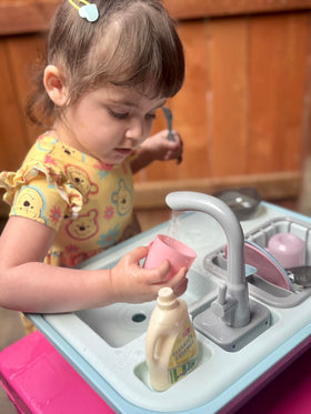 Asweets toddler plays with sink toy for imaginative kitchen role-play.