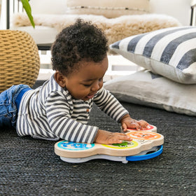 Baby using the drum in a cozy playroom setup.