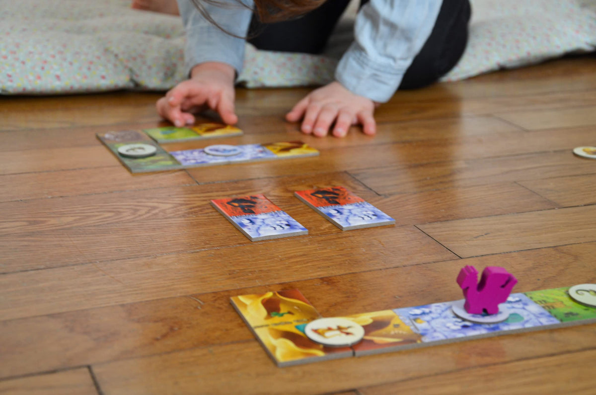 Blue Orange Dragomino mommy dragon meeple guiding family-friendly play.