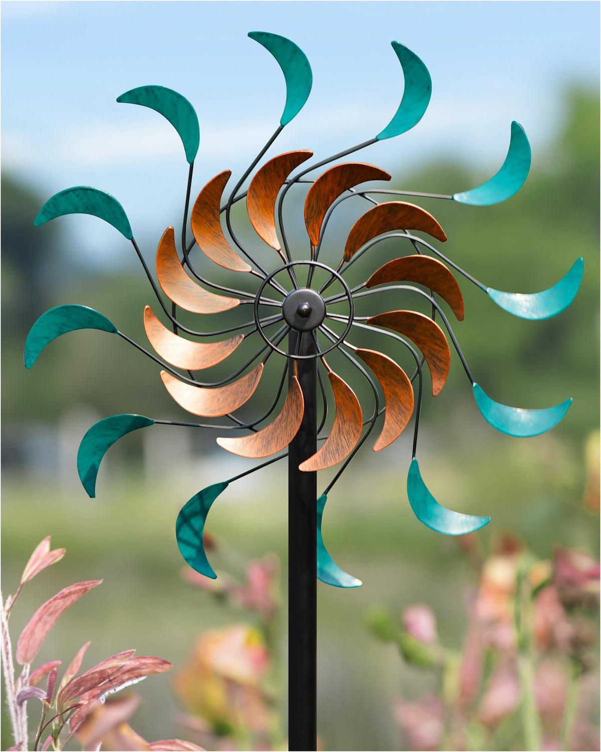 Cyan Oasis wind spinner in garden, 13x54 inches, adds vibrant focal point.