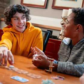 Envy Born Games in-action scene shows family sharing laughter around the table.