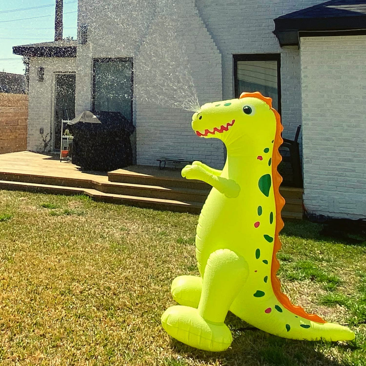 Kids enjoying water play around a Float Joy dino sprinkler in the yard.