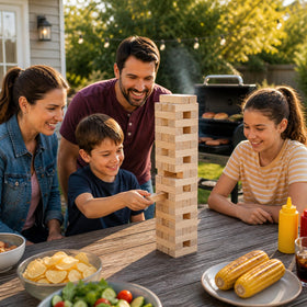 Kids and adults play a tower game outdoors with Giantville blocks.