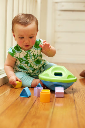 Child plays sorting shapes with Green Toys Shape Sorter to develop motor skills