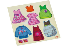 HABA Dress-Up Doll Magnetic Game Box shows little hands placing magnet pieces to build outfits