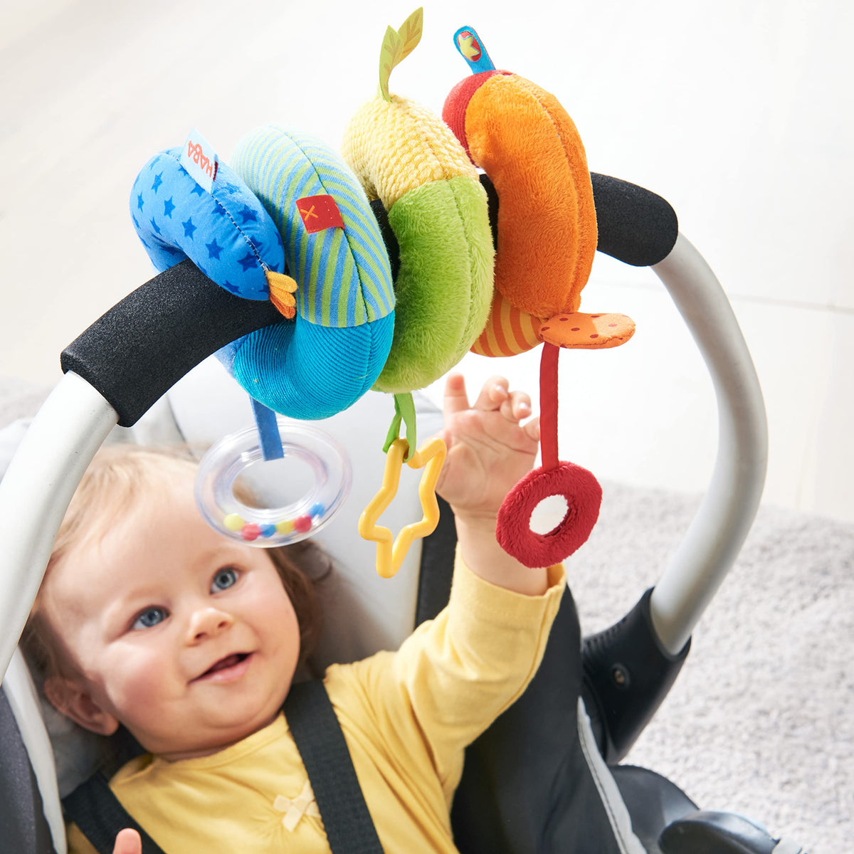 HABA Rainbow Activity Spiral on a stroller with teether and gentle rattle