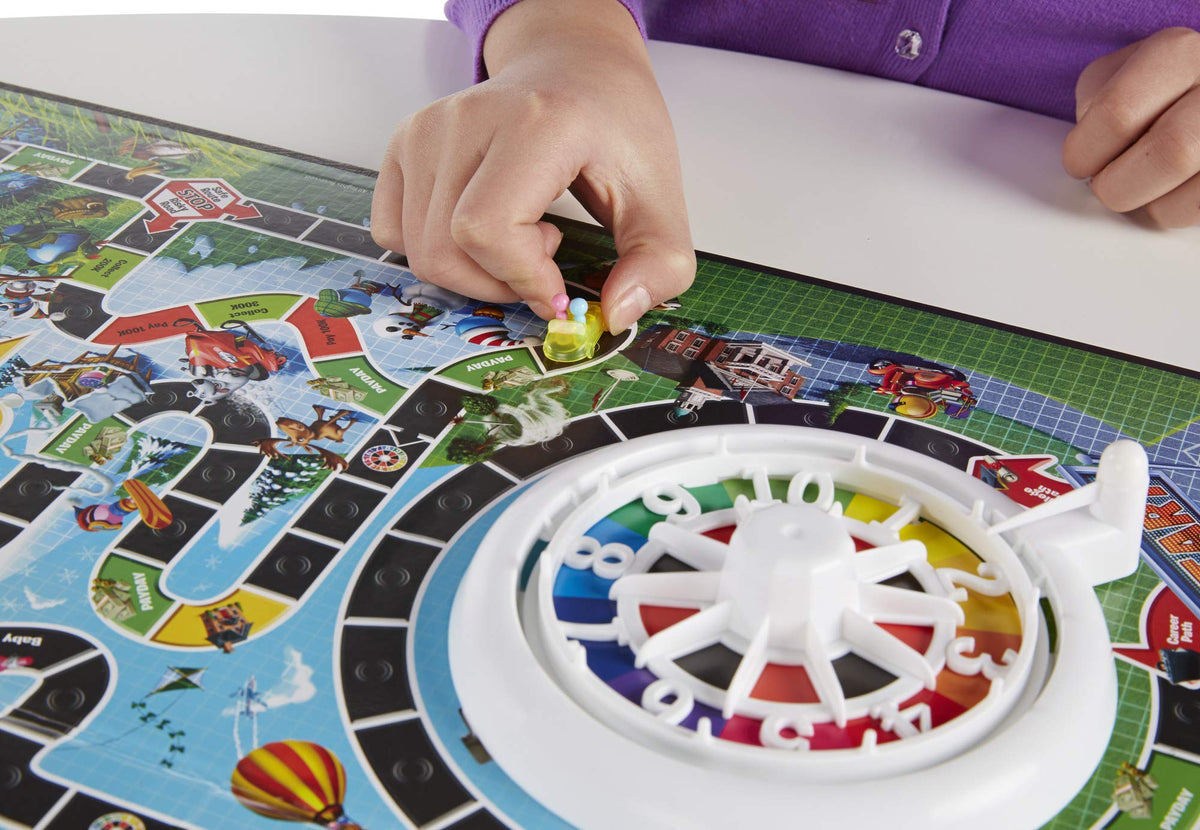 Hasbro Gaming The Game of Life family playing together during a lively game night.