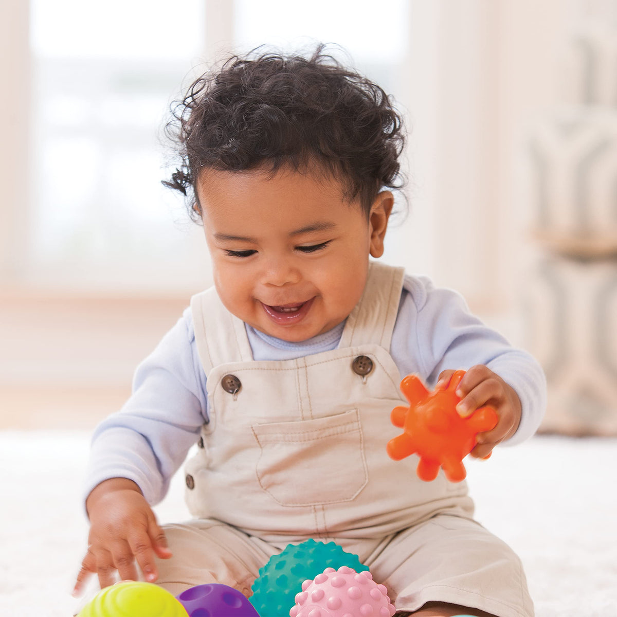 Baby reaches and grabs Infantino balls showing engaging texture variety.