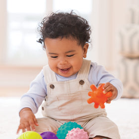 Baby reaches and grabs Infantino balls showing engaging texture variety.
