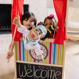 Clock with movable hands on Melissa and Doug puppet theater for cueing stories.