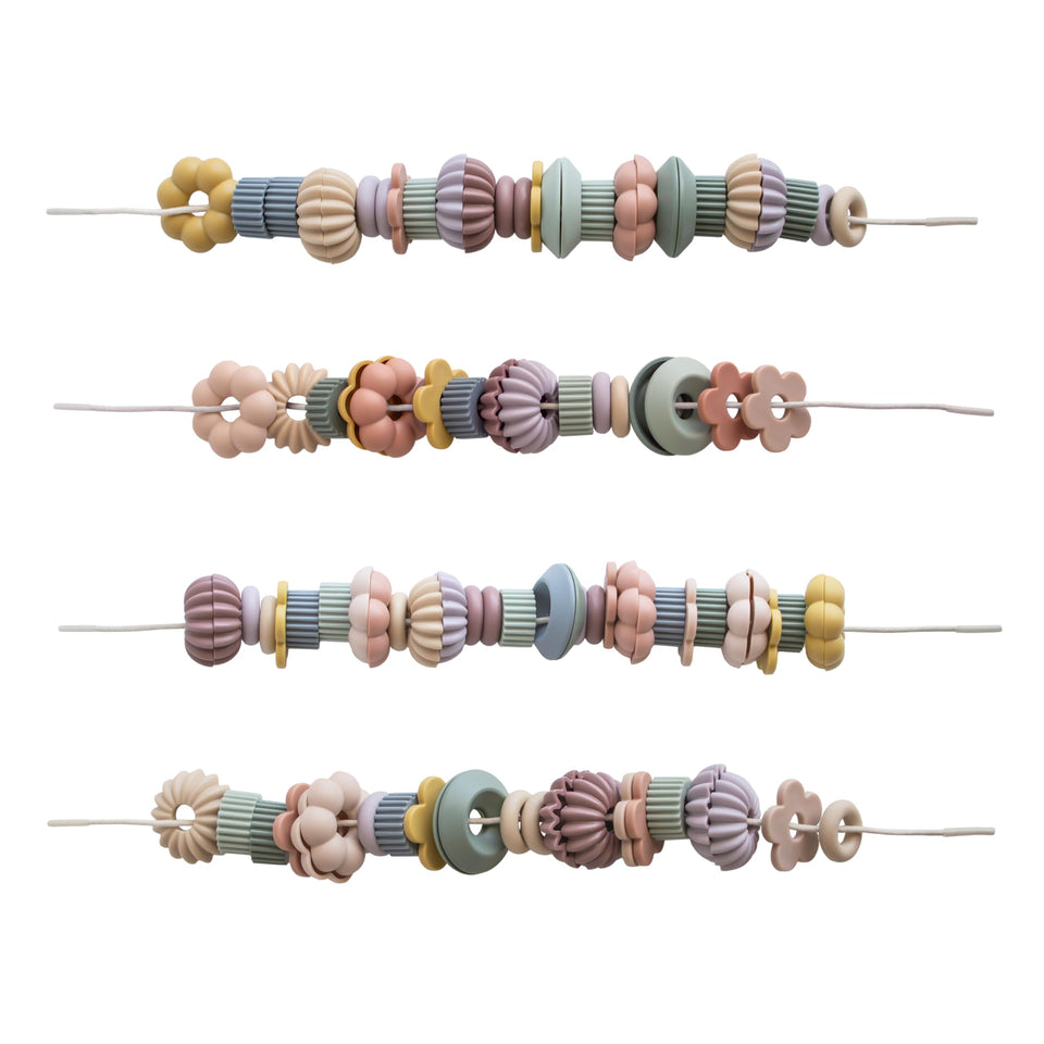 Mushie Bead Lacing Toy Set beads and strings supporting fine motor play.