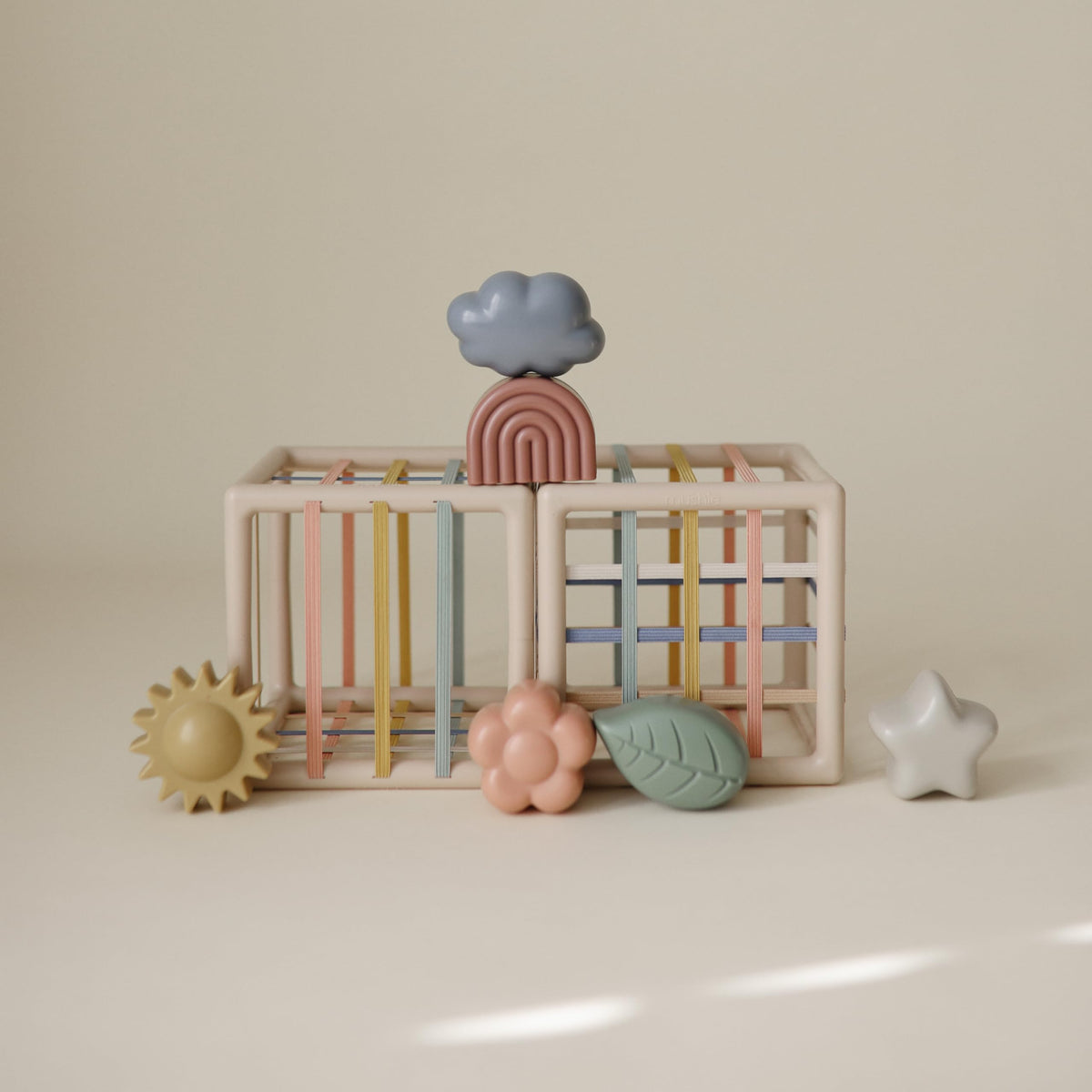 Mushie Elastic Shape Sorter invites little hands to stretch into openings