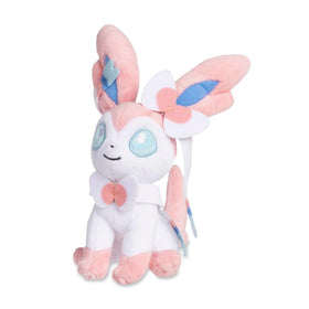 Pokémon Center Sylveon Sitting Cuties Plush on desk sits upright for display.