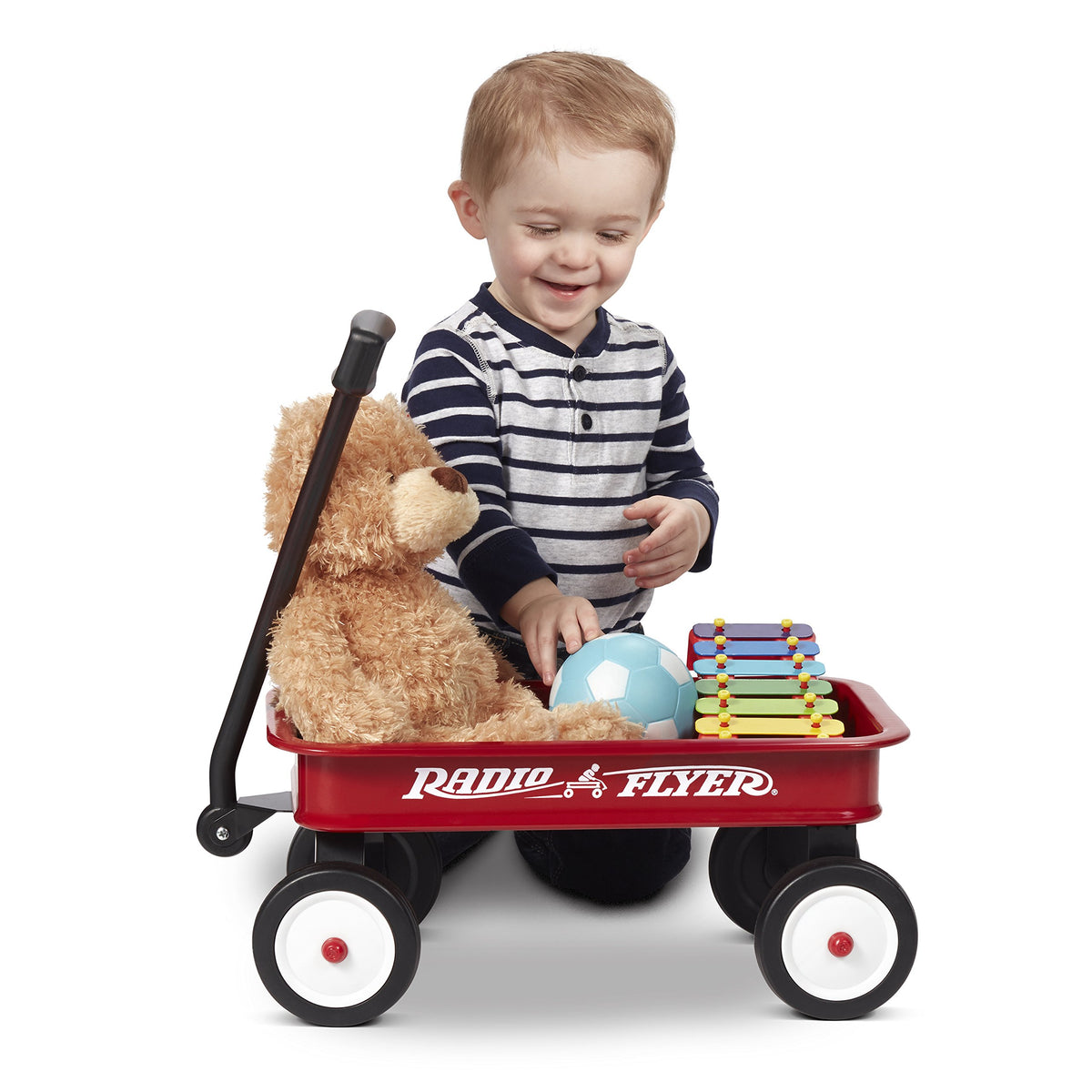 Radio Flyer Mini Classic Red Wagon carrying dolls and small toys.