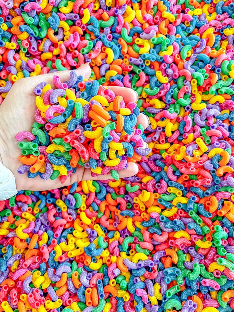 Sensory-N-Stuff rainbow elbow pasta enhances imaginative play in dry bins.