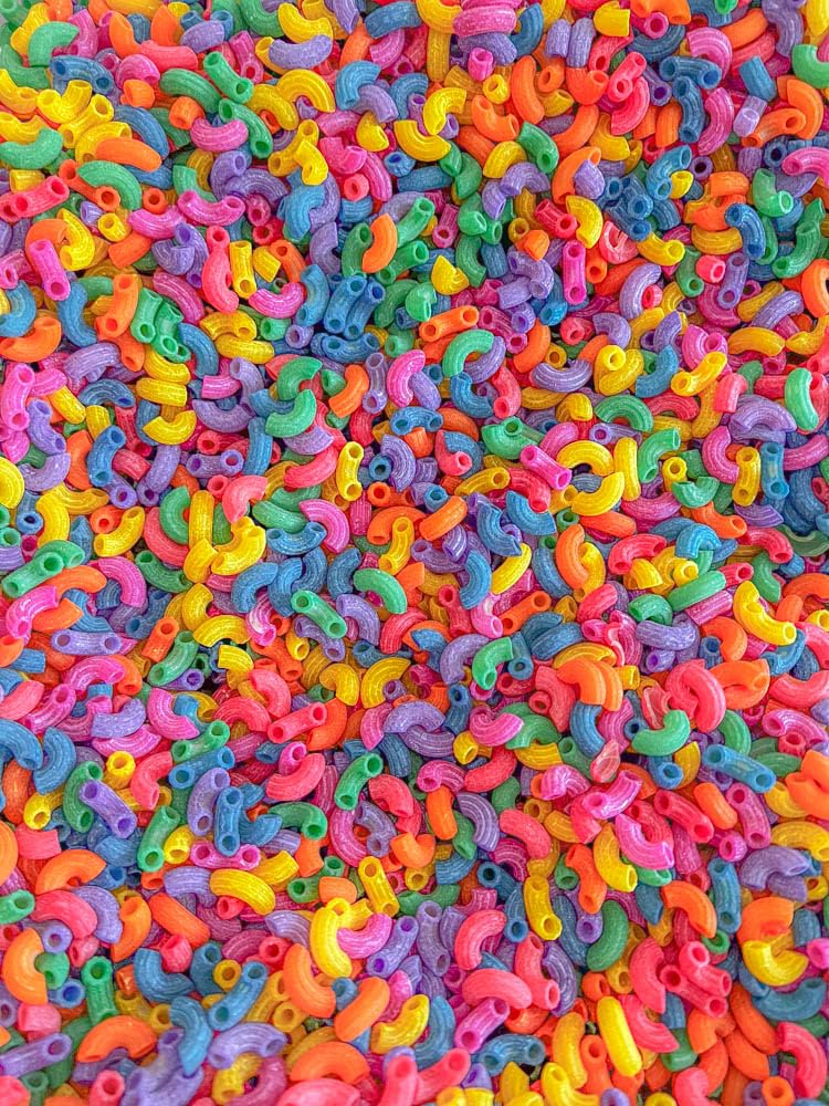 Sensory-N-Stuff rainbow elbow pasta supports scooping and sorting activities.