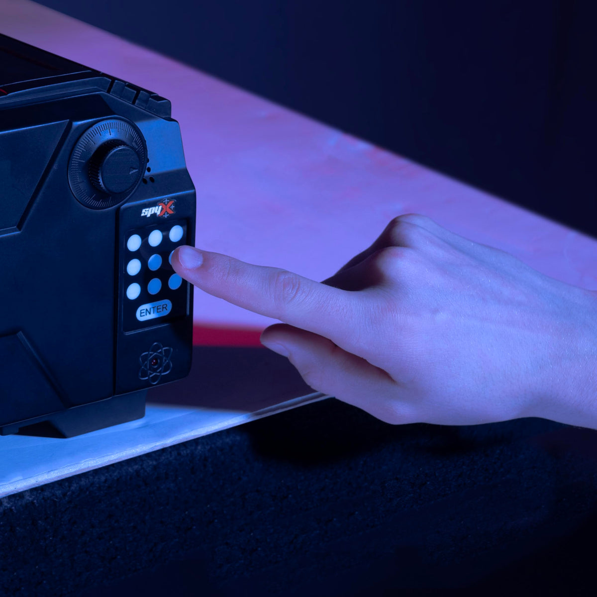 Kid demonstrates code entry on SpyX Alarm Safe, encouraging problem-solving.