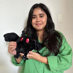Squishable Snugglemi Snackers Baby Mothman in a bedroom decor setting