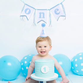 WAOUH blue and white banner ribbons frame the first birthday backdrop