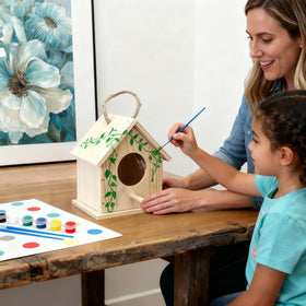 Hot glue gun in use for quick, strong birdhouse assembly.